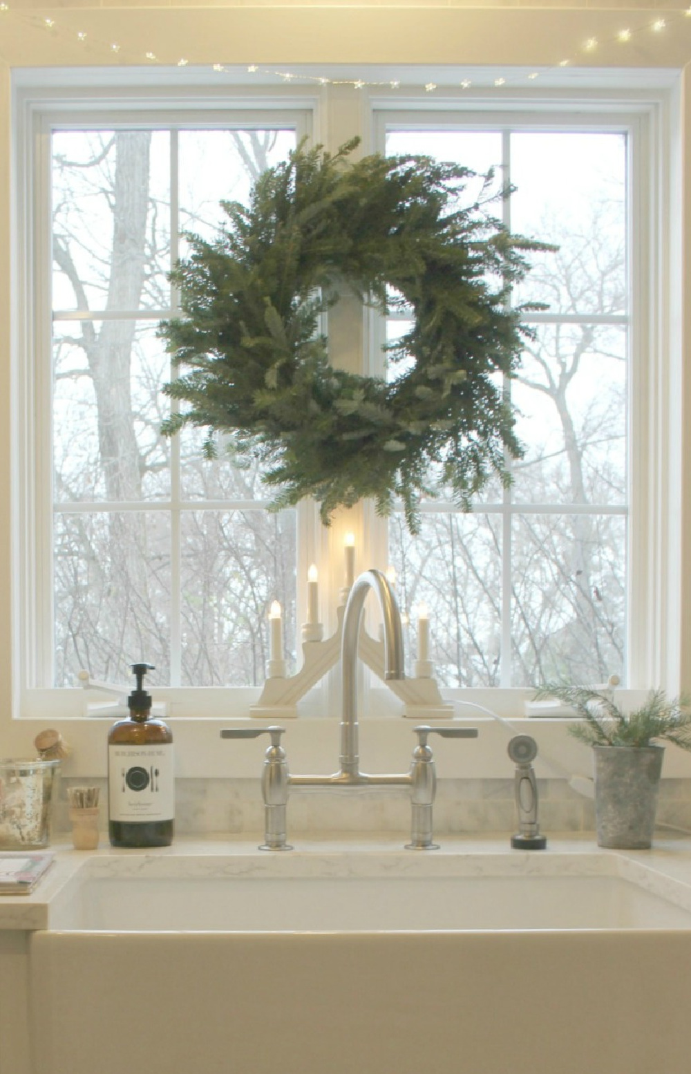 A beautiful Frasier fir wreath, Swedish candelabra, and white fairy lights over my modern farmhouse sink for the holidays. #modernfarmhouse #farmsink #farmhousedecor #Christmaswreath #SwedishChristmas