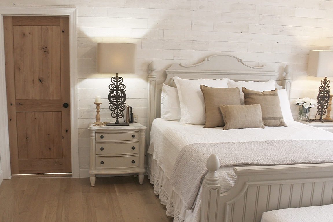 White French country cottage bedroom with Stikwood (hamptons) statement wall, white oak hardwood, and rustic alder doors. #hellolovelystudio #frenchcountry #bedroomdecor #rusticelegance #whiteoak #frenchbedrooms #alderdoor #stikwood #hamptons #romanticdecor #whitebedrooms #interiordesign