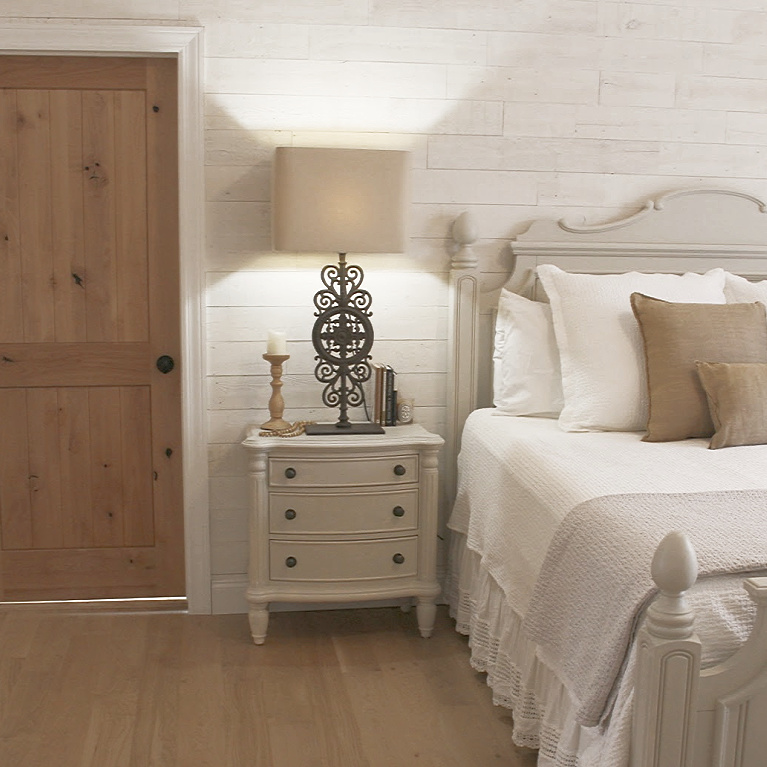 White French country cottage bedroom with Stikwood (hamptons) statement wall, white oak hardwood, and rustic alder doors. #hellolovelystudio #frenchcountry #bedroomdecor #rusticelegance #whiteoak #frenchbedrooms #alderdoor #stikwood #hamptons #romanticdecor #whitebedrooms #interiordesign