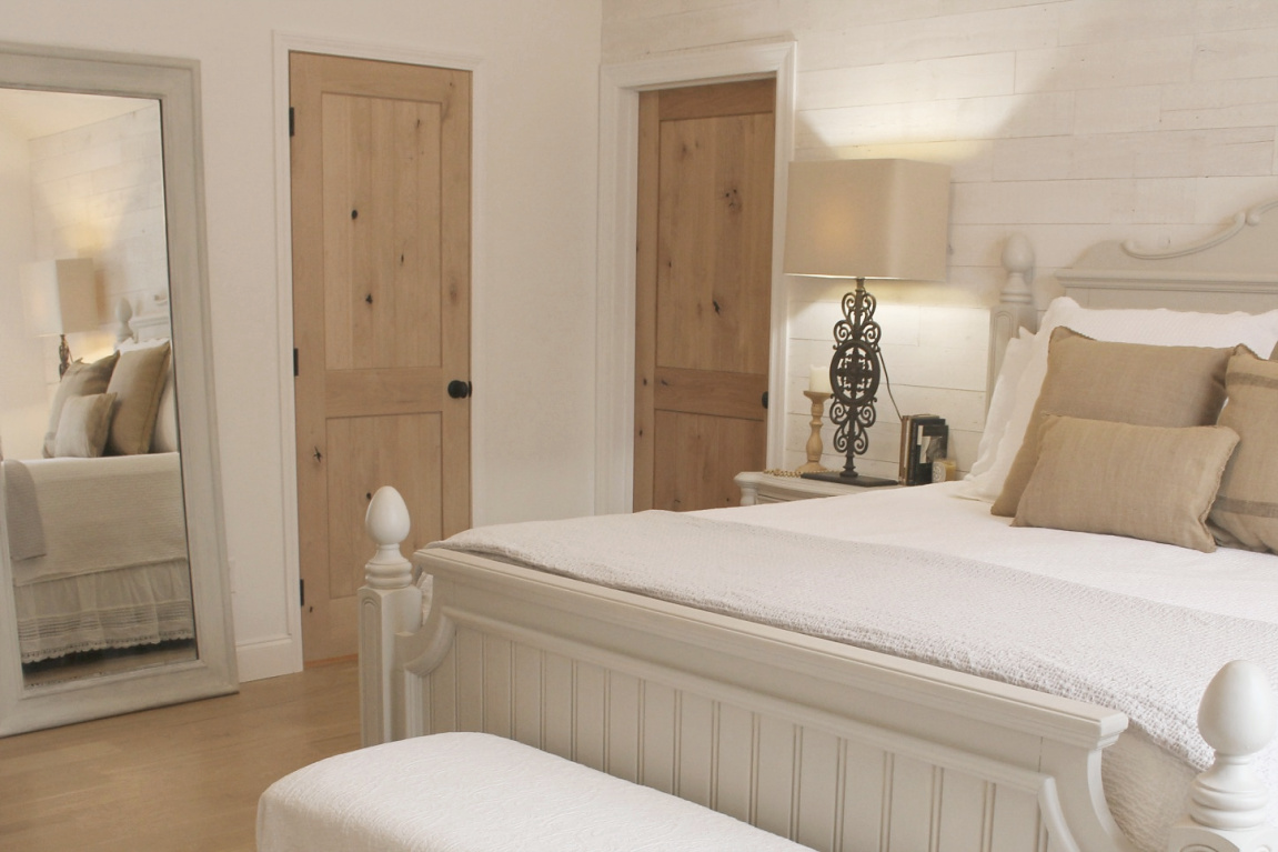 White French country cottage bedroom with Stikwood (hamptons) statement wall, white oak hardwood, and rustic alder doors. #hellolovelystudio #frenchcountry #bedroomdecor #rusticelegance #whiteoak #frenchbedrooms #alderdoor #stikwood #hamptons #romanticdecor #whitebedrooms #interiordesign