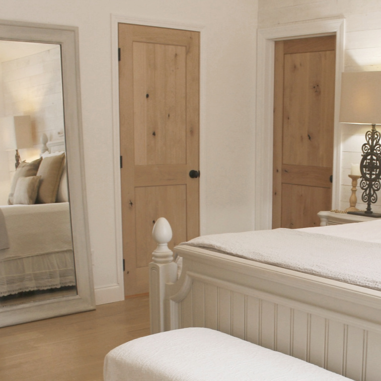 White French country cottage bedroom with Stikwood (hamptons) statement wall, white oak hardwood, and rustic alder doors. #hellolovelystudio #frenchcountry #bedroomdecor #rusticelegance #whiteoak #frenchbedrooms #alderdoor #stikwood #hamptons #romanticdecor #whitebedrooms #interiordesign