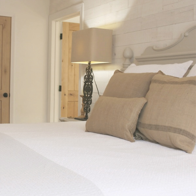 White French country cottage bedroom with Stikwood (hamptons) statement wall, white oak hardwood, and rustic alder doors. #hellolovelystudio #frenchcountry #bedroomdecor #rusticelegance #whiteoak #frenchbedrooms #alderdoor #stikwood #hamptons #romanticdecor #whitebedrooms #interiordesign