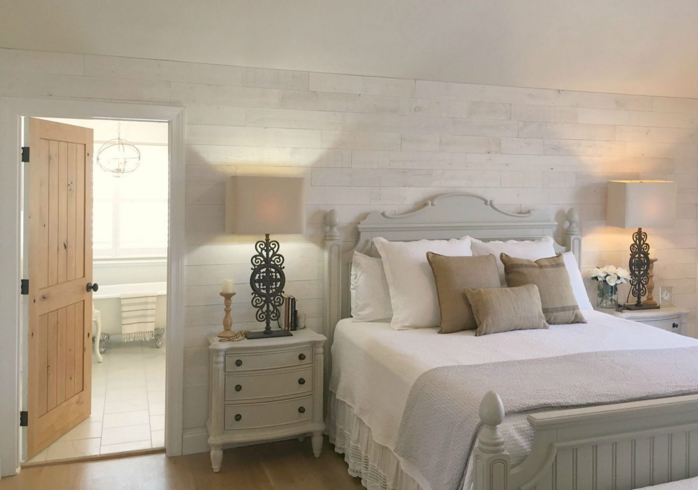 My serene white bedroom with Stikwood (Hamptons) statement wall, cottage style furniture, knotty alder door with oiled bronze hardware, and white oak wide plank hardwood flooring. #hellolovelystudio #bedroom #serene #whitebedroom #frenchcountry #rusticdecor #modernfarmhouse #stikwood #hamptons