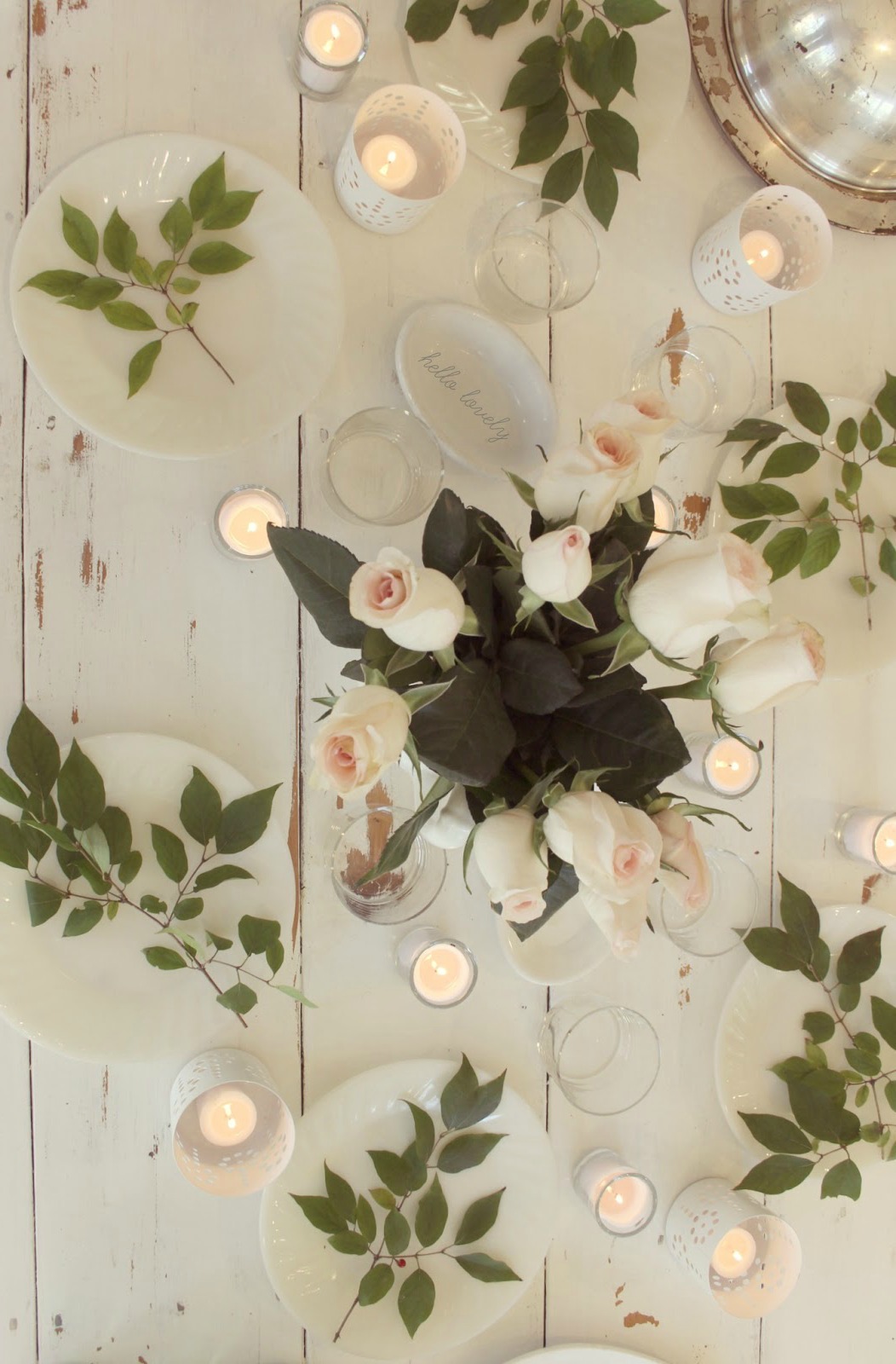 My romantic farmhouse tablescape with blush roses, branches, and candelight upon a distressed white #farmtable. #tablescape #hellolovelystudio