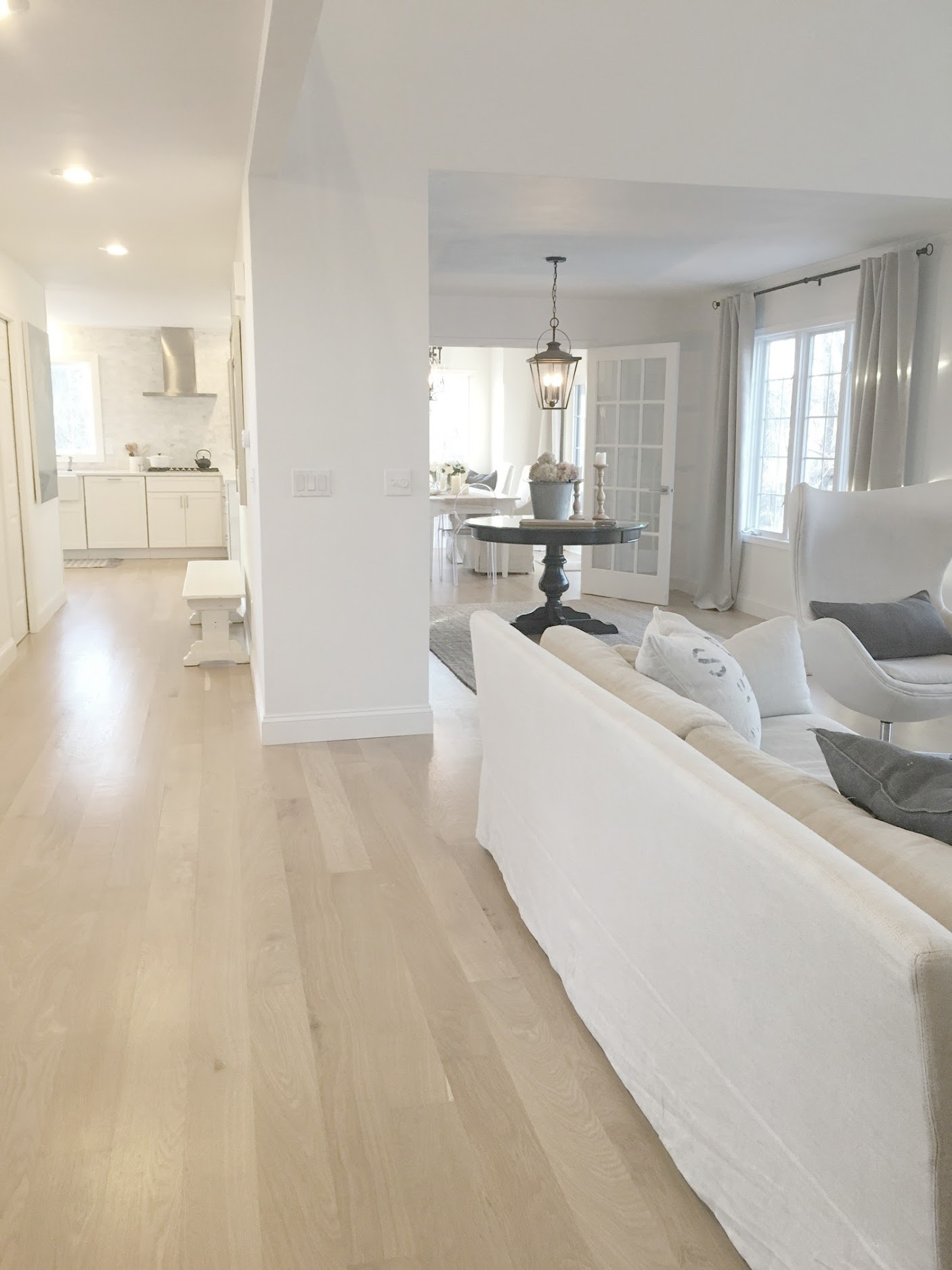 White decor in a completely renovated Chicagoland cottage with modern farmhouse style by #hellolovelystudio. White oak flooring, Belgian linen upholstery, and a white classic kitchen with Shaker style cabinetry.