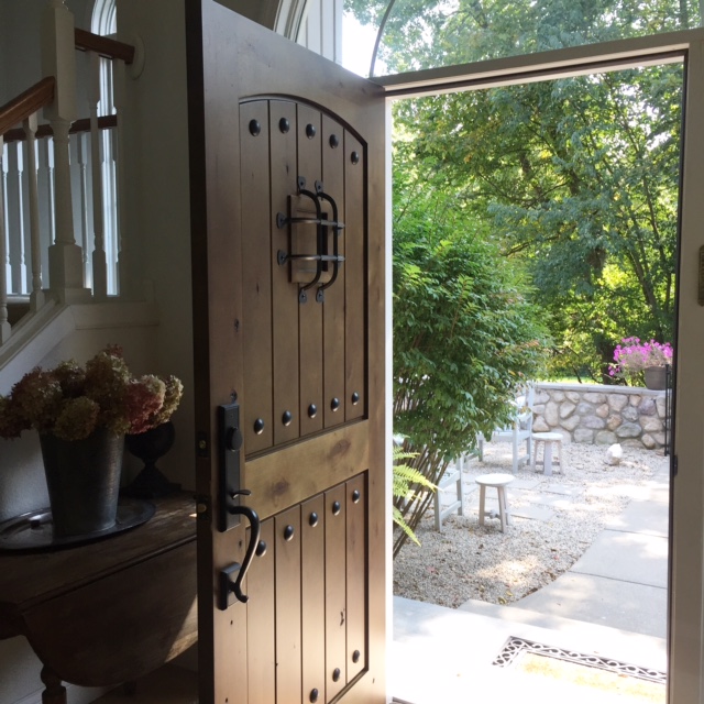 European country inspired entry with rustic alder front door with speakeasy. Hello Lovely Studio is a blog with French country inspired interiors, French farmhouse decor, and interior design inspiration overflowing with timeless and tranquil charm.