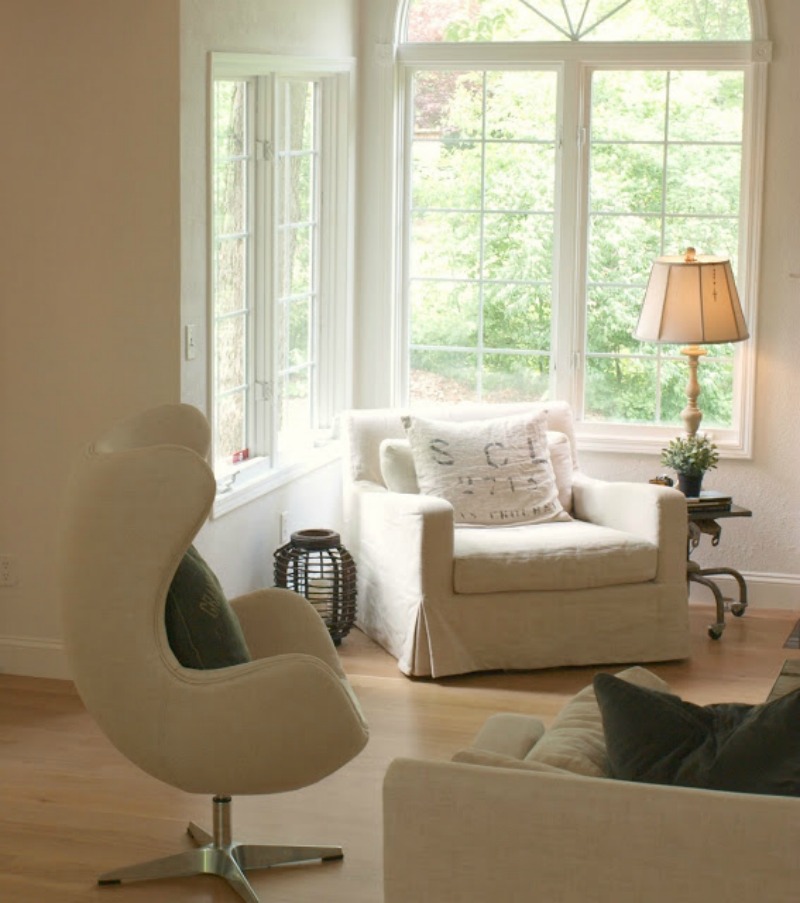 Belgian linen upholstered furniture in a spare yet cozy living room with European country style by Hello Lovely Studio.