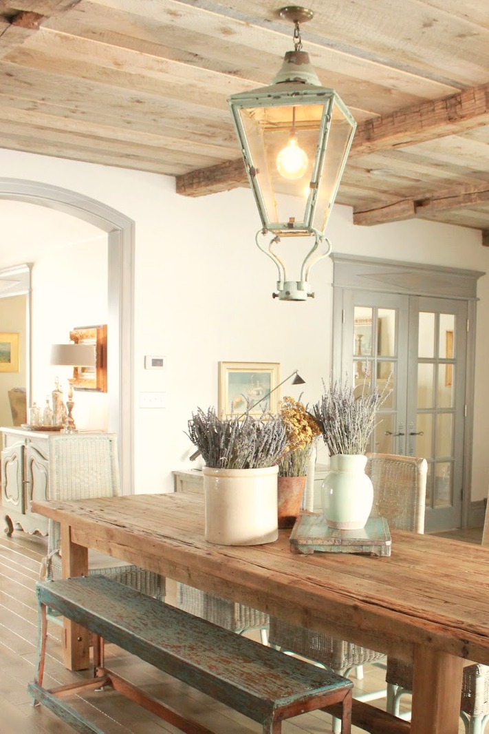 Magnificent Gustavian French stone dining room in cottage with rustic interiors, reclaimed wood ceilings, blue-grey, green, and collected European antiques. Designed by Desiree Ashworth. Find ideas for grey, blue, and green paint colors.