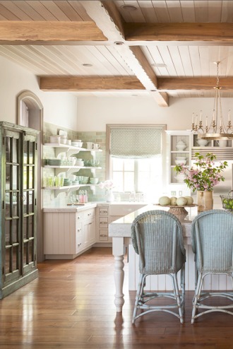 Natural light streams into a French Country kitchen with warm wood ceiling, white cabinetry, antique cabinet, open shelving, and aqua tile and accents. Decor de Provence. #FrenchCountry #Nordicdecor #Farmhousekitchen