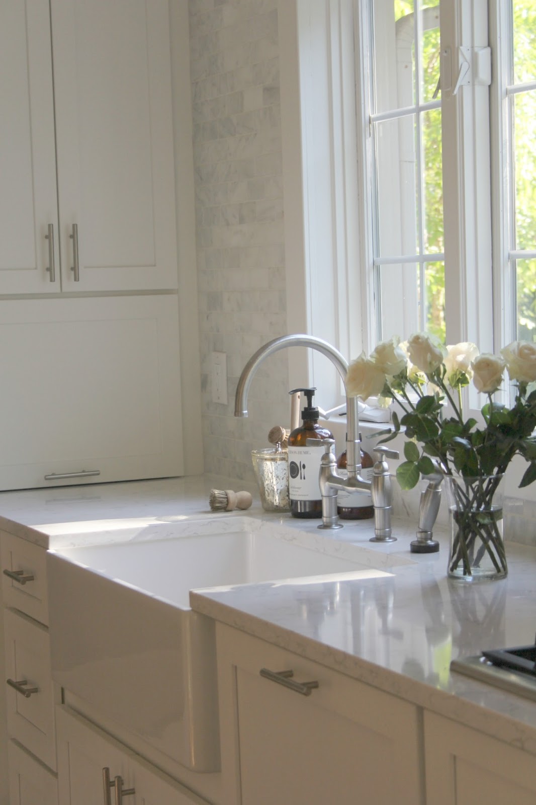 Serene white kitchen with Shaker cabinets, fireclay apron front farm sink, bridge faucet, Viatera quartz countertop (Minuet), and marble subway tile backsplash -hello lovely studio. Let's chat about how to decorate chic yet cheap! #kitchen #whitekitchen #serene #classic #quartz #subwaytile #viateraquartz #minuet