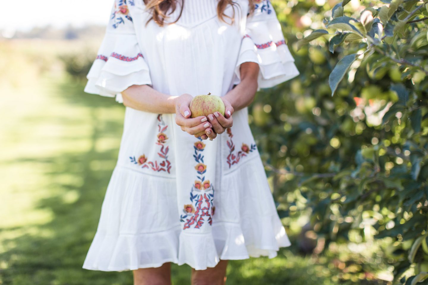 Leslie of Lemon Grove Lane in boho dress holding apple.