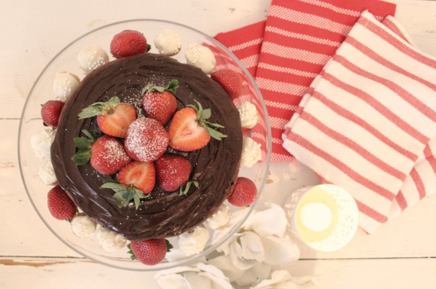 Beautiful chocolate cake with berries on pedestal with red and white napkins - Hello Lovely Studio