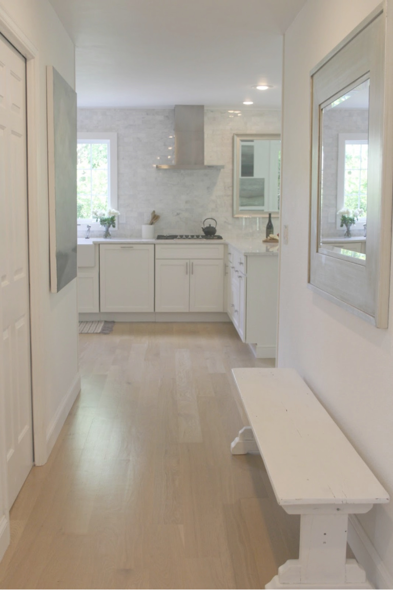 Hello Lovely's white modern French kitchen with white oak hardwoods, Shaker cabinets, Viatera Minuet quartz counters, modern Italian range hood, and polished marble subway tile backsplash taken to ceiling.