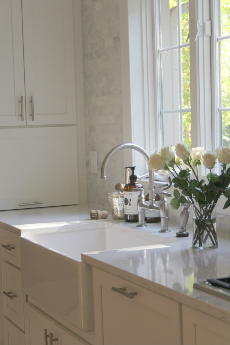 White Shaker cabinetry and apron front fireclay sink in my serene white kitchen with Viatera quartz (Minuet) and polished marble subway tile backsplash. #hellolovelystudio #kitchendesign #farmsink #shakerkitchen #whitekitchen #frenchcountry #subwaytile #serenekitchen