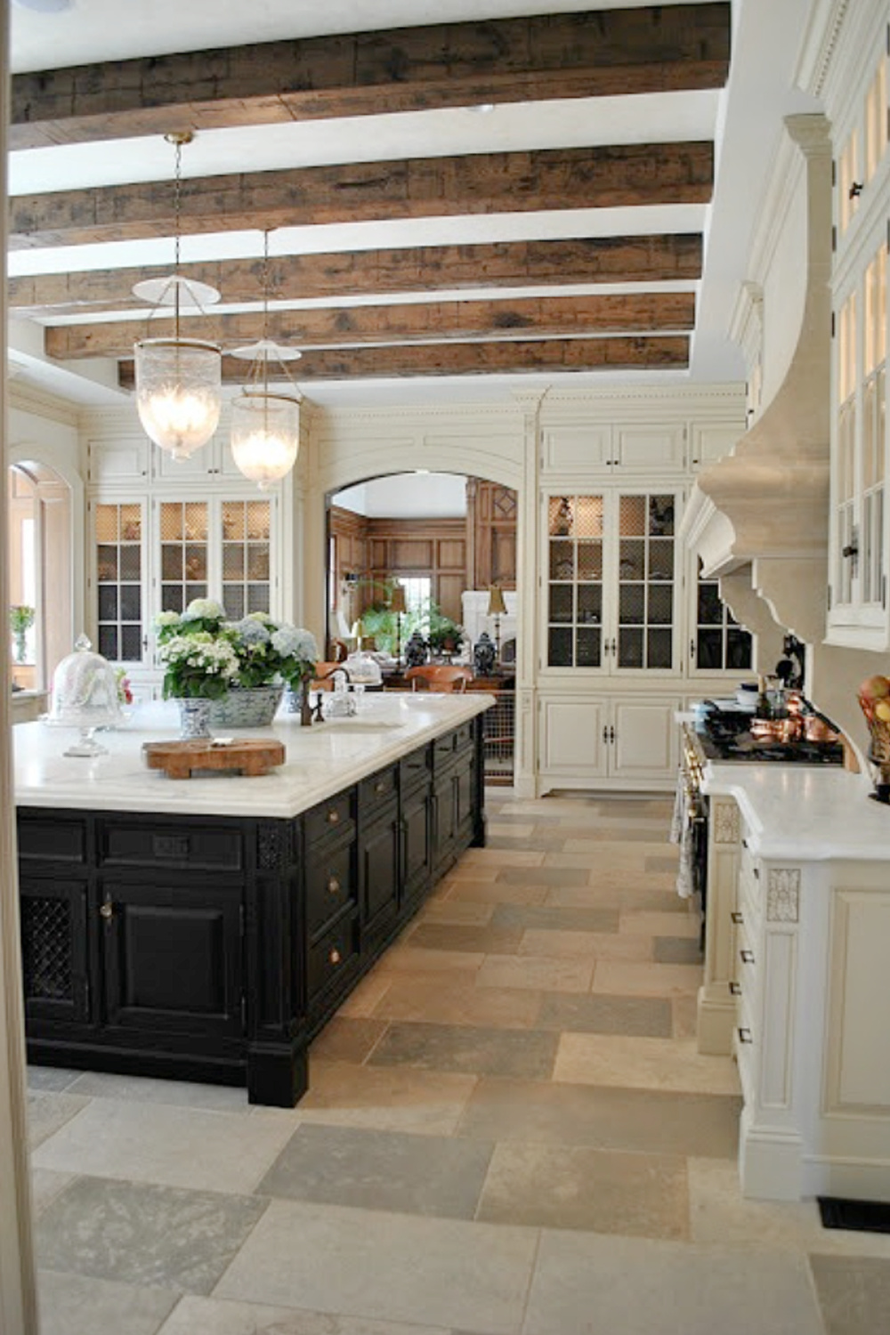 Stunning European Country kitchen with black island, wood celing beams, bell jar pendant lights, and marble counters. #FrenchCountry #kitchendesign