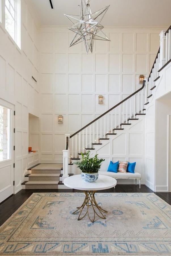 Wimborne White paint color by Farrow & Ball in a magnificent home's entry with soaring ceilings, paneled walls, and elegant staircase. #wimbornewhite #farrowandball #paintcolors #bestwhitepaintcolors