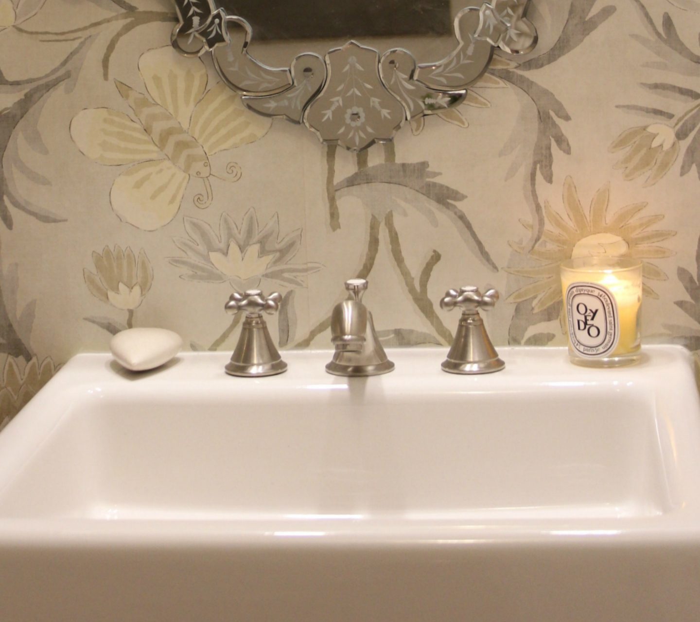 Classic bathroom design with fireclay farmhouse sink, brushed nickel faucet, Venetian mirror, and light grey wallpaper with butterflies. #DIYbathroom #bathroomdesign #farmsink