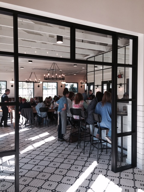 Magnolia Table restaurant interior with black and white floor tile, farmhouse style chandeliers, and redwood beams. #magnoliatable #farmhouse #restaurant #fixerupper