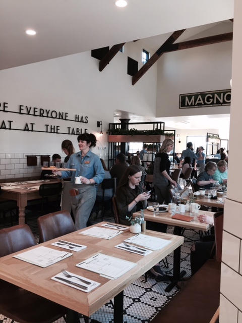 Magnolia Table restaurant interior with black and white decor and natural wood tables. #magnoliatable #restaurant #fixerupper #waco