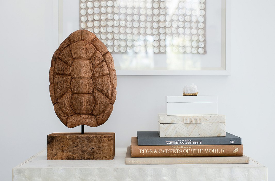 A piece of dried barn wood, carved to resemble a tortoiseshell, creates the right exclamation point on a bar cart in Erin Fetherston's white living room #chantillylace #paintcolors #whitepaint #modernrustic #allwhite #interiordesign