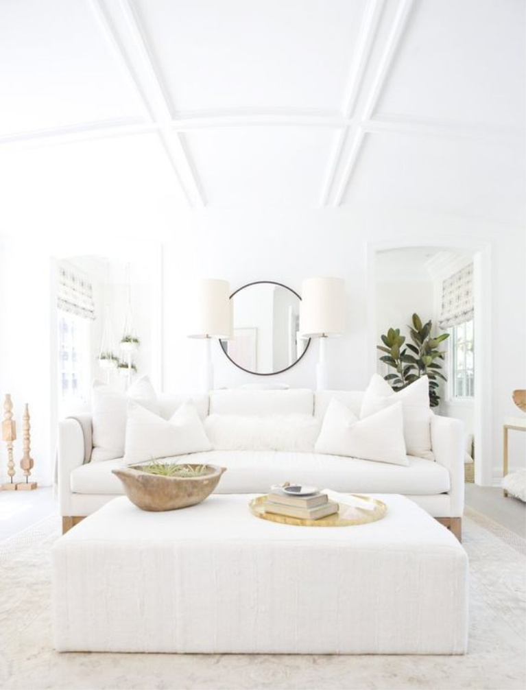 All white living room with white linen sofa, upholstered ottoman, rustic dough bowl, brass accents, and California modern farmhouse chic by Erin Fetherston. #whitedecor #livingroom #whiteonwhite #toneontone #interiordesign #whitelinen #modernrustic