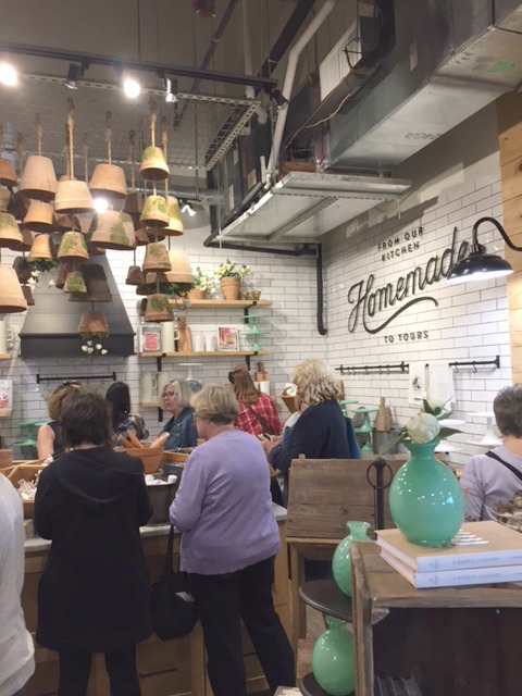 Het interieur van Magnolia Market at the Silos met witte vloertegels, terracotta potten aan het plafond en een inrichting in boerderijstijl. #magnoliamarket #silos #waco #fixerupper