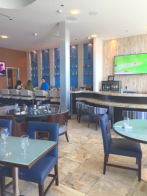 Brazos Bar & Bistro with Travertine floor, blue decor, and Midcentury Modern details within #hotelindigo in #Waco