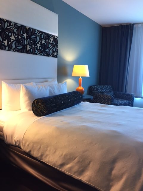Hotel Indigo Waco blue bedroom interior with dramatic headboard, white bedding, and Midcentury Modern decor. #hotelindigo #waco #midcenturymodern #bedroom