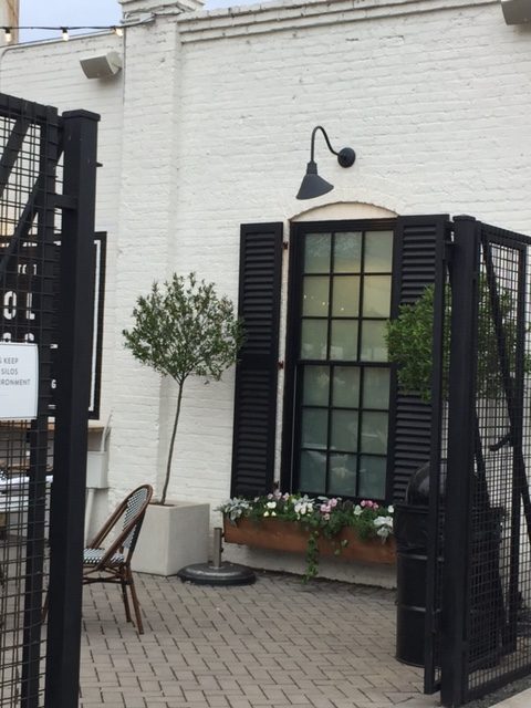 Silos Baking Co. exterior at Magnolia Market in Waco, Texas. Black shutters, barn style black lighting, white brick, and black and white decor. #silosbakingco #magnoliamarket #fixerupper