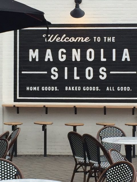 Magnolia Market Silos witte bakstenen muur van Silos Baking Co. met barkrukken, Parijse bistrostoelen, en zwart-witte inrichting. #magnolia #silos #bakery #fixerupper