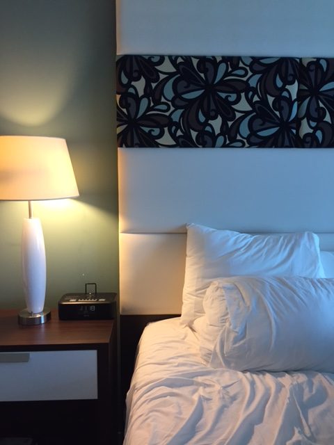 Hotel Indigo upholstered headboard and night table with Midcentury Modern white lamp. #hotelindigo #bedroomdecor #midcenturymodern