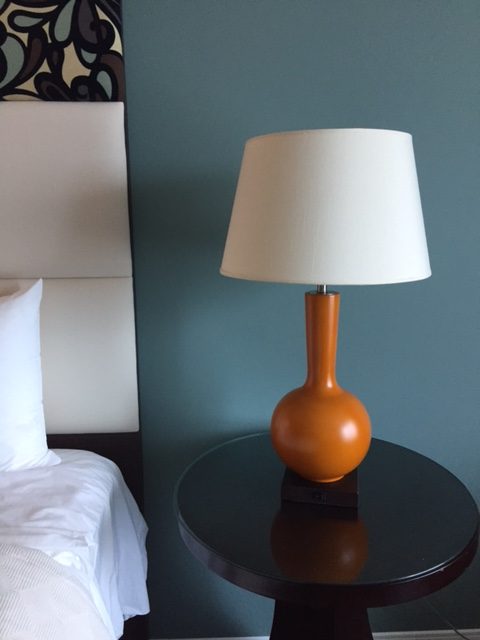 Teal blue wall and orange Midcentury modern lamp at Hotel Indigo Waco. #bedroomdecor #orange #teal #Midcenturymodern