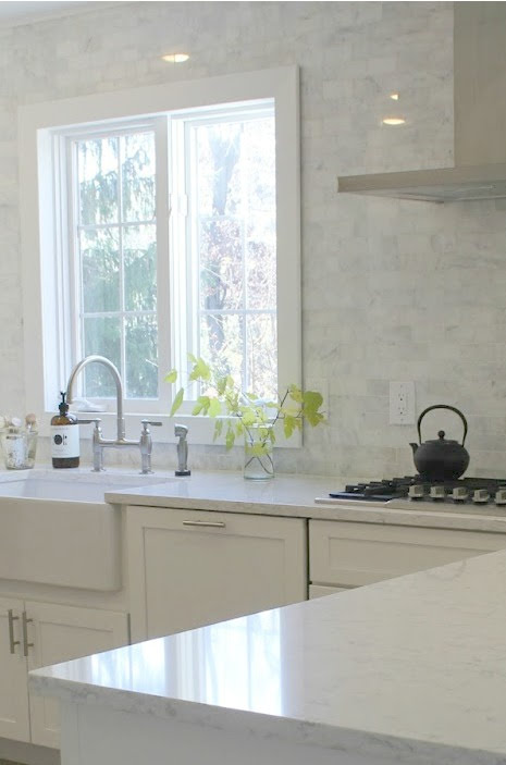 Timeless, tranquil, French farmhouse and European country style white kitchen has soft linen, polished marble backsplash and Viatera Minuet white quartz countertop. Hello Lovely Studio.