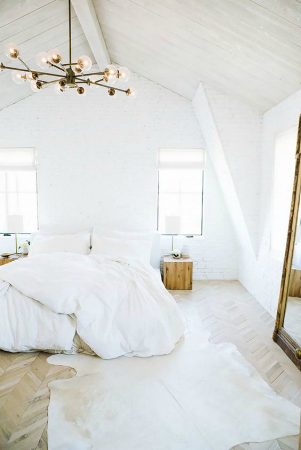 Stunning and serene all white decor in a bedroom design by Leanne Ford. Midcentury-modern style, Sputnik chandelier, herringbone flooring, and hide rug. #whitebedroom #allwhite #bedroomdecor #midcenturymodern #leanneford