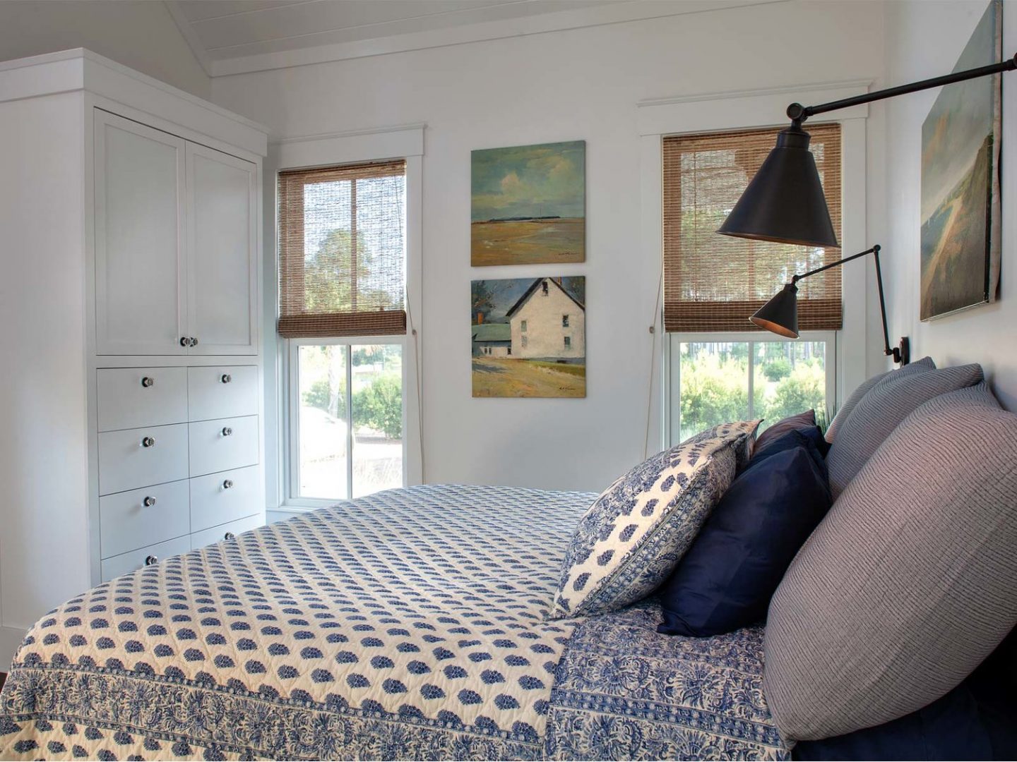 Blue and white coastal bedroom with paisley quilt, swing arm modern sconces, and tranquil paintings. Interior design by Lisa Furey. #blueandwhite #coastalbedroom #interiordesign #beachystyle