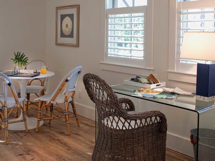 Parisian bistro chairs cozy up to a tulip table alongside a work area with rattan chair and modern acrylic waterfall desk. Interior design by Lisa Furey. #interiordesign #coastalstyle #diningchairs #furniture