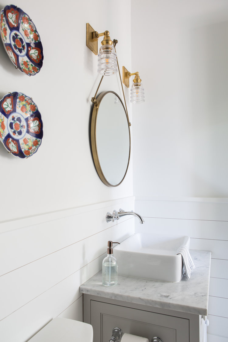 Coastal bathroom with shiplap, vessel sink, and round mirror.Board and batten coastal cottage in Palmetto Bluff with modern farmhouse interior design by Lisa Furey.