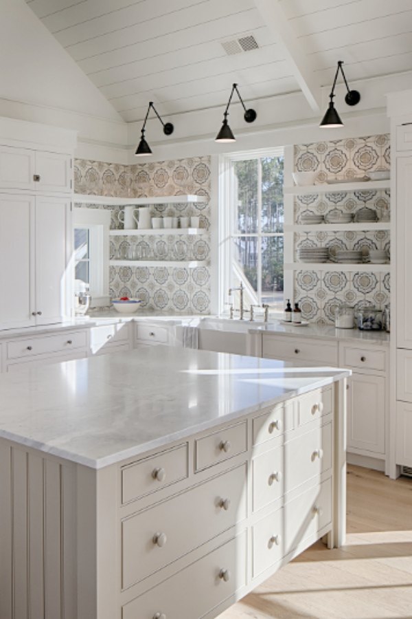 Lisa Furey's white coastal cottage kitchen in Palmetto Bluff inspires with its colorful tile, quiet grey island, and modern black wall sconces. Click through for Perfect Light Gray Paint Colors You'll Love as Well as Interior Design Inspiration Photos. #bestgreypaint #paintcolors