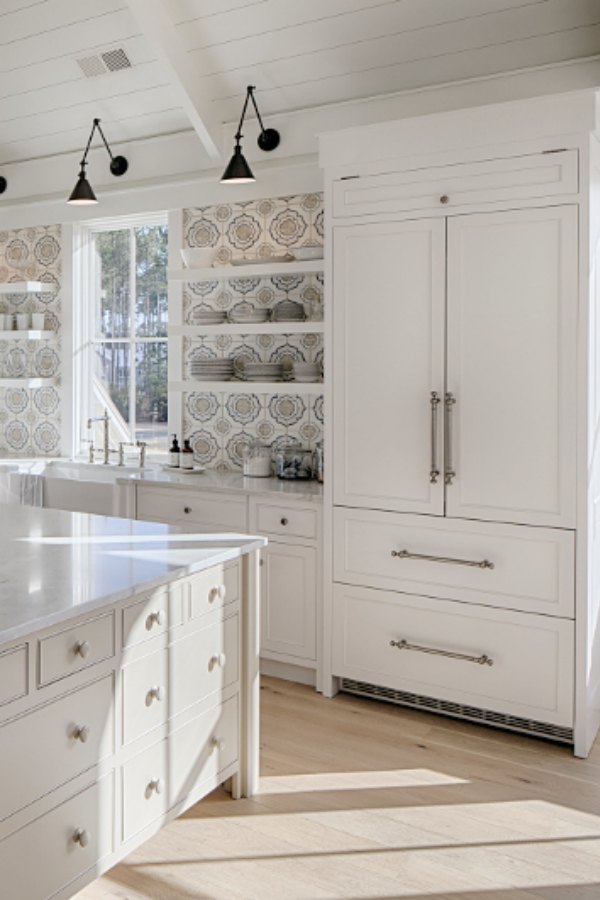 Lisa Furey's white coastal cottage kitchen in Palmetto Bluff inspires with its colorful tile, quiet grey island, and modern black wall sconces.