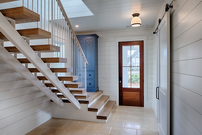 White oak staircase, blue painted cabinet, and shiplap in entryway. Board and batten coastal cottage in Palmetto Bluff with modern farmhouse interior design by Lisa Furey.