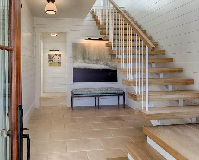 White oak hardwood flooring and floating staircase in entry.Board and batten coastal cottage in Palmetto Bluff with modern farmhouse interior design by Lisa Furey.