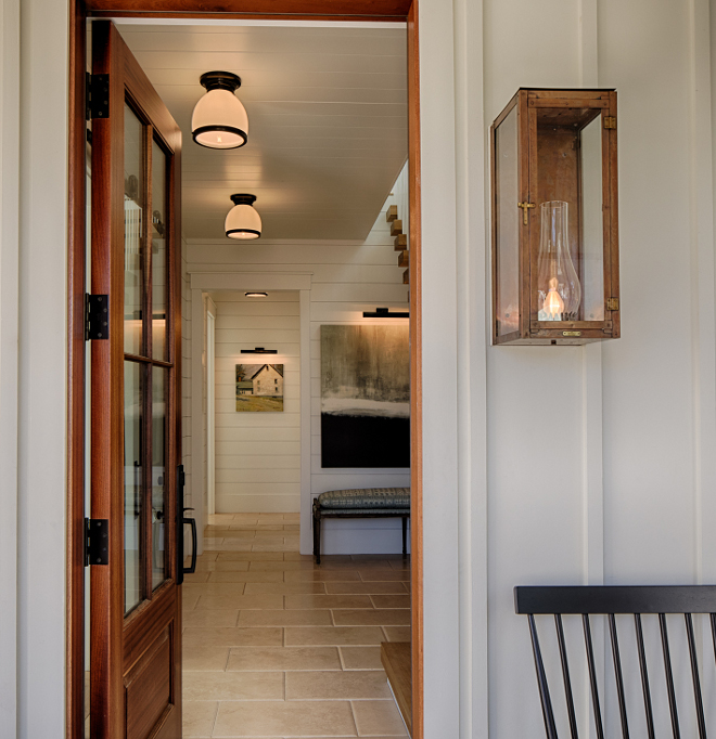 Front porch with amazing modern lantern sconce and view of entry with shiplap. Board and batten coastal cottage in Palmetto Bluff with modern farmhouse interior design by Lisa Furey. #entry #shiplap #modernfarmhouse #interiordesign #coastalstyle