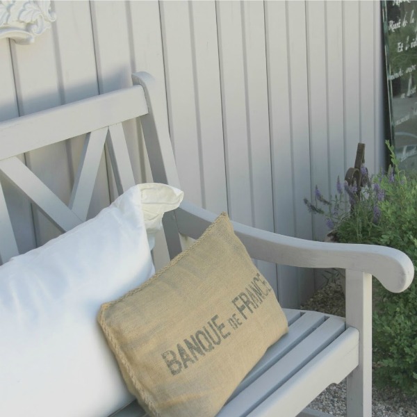 Our French country inspired French courtyard is simple and easy to maintain with its pea gravel, painted distressed furniture, and boxwood plantings - Hello Lovely Studio.