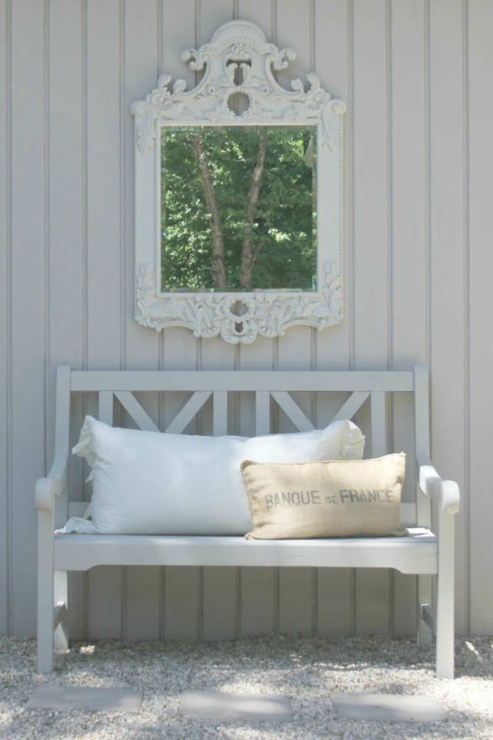 Charming French inspired courtyard with gravel, bench, and ornate French mirror. Design by Hello Lovely Studio. #courtyard #frenchcountry #bench #mirror #outdoor living