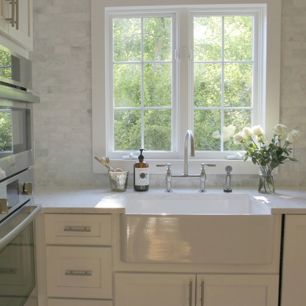 White classic kitchen with Shaker cabinets, farm sink, and carrara marble subway tile. Design by Hello Lovely Studio. #whitekitchen #modernfarmhouse #classickitchen #farmsink #carraramarble #backsplash