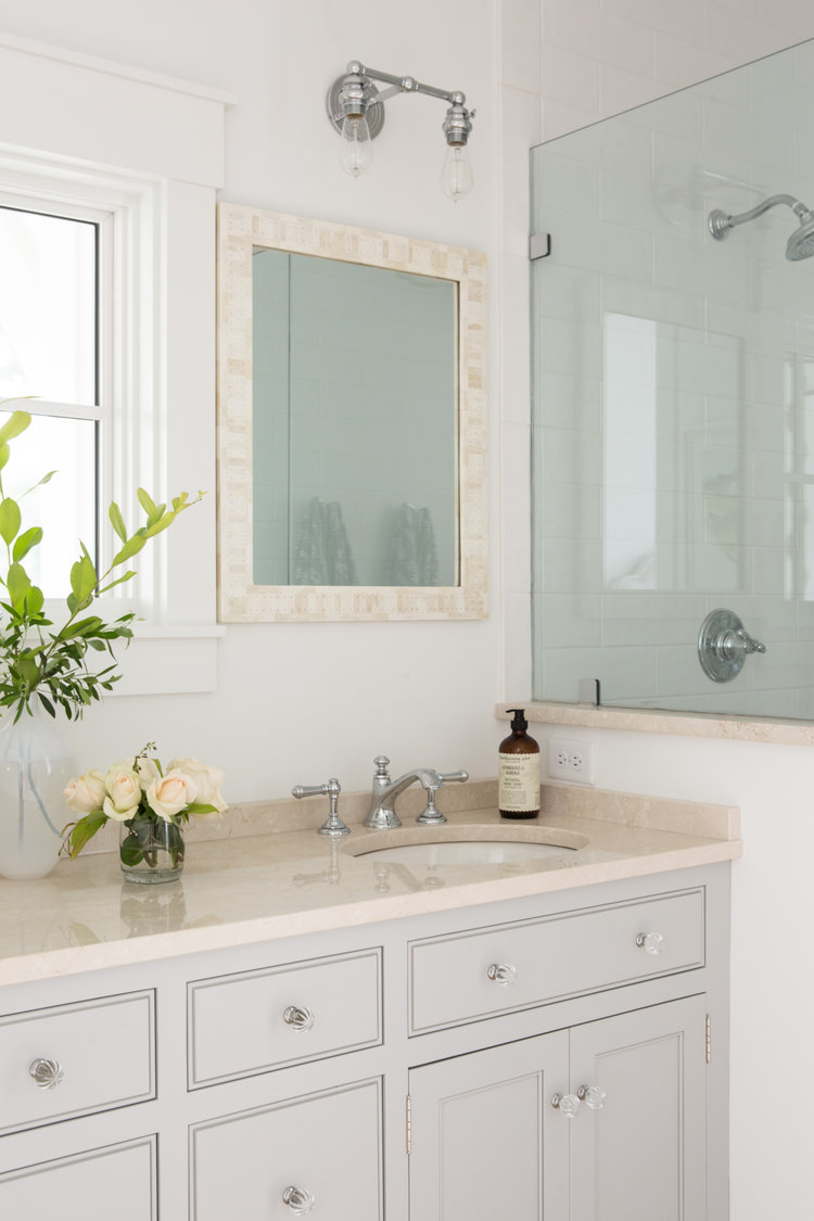 Double vanity with mother of pearl framed mirrors in a South Carolina coastal cottage bathroom by Lisa Furey. #bathroomdesign #lightgrey #coastalstyle #interiordesign #traditionalstyle