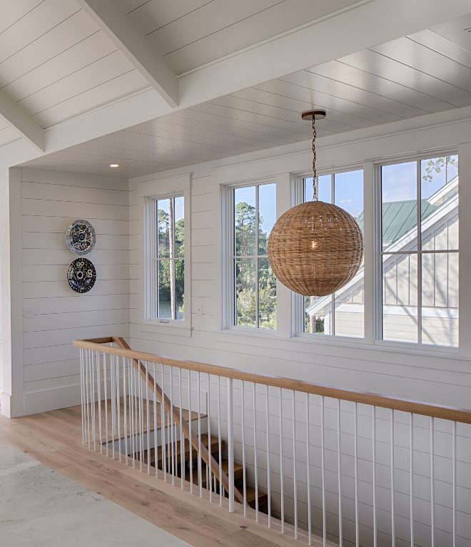 Staircase with rattan globe chandelier in a board and batten coastal cottage in Palmetto Bluff. Modern farmhouse interior design by Lisa Furey. #shiplap #staircase #coastalcottage #interiordesign