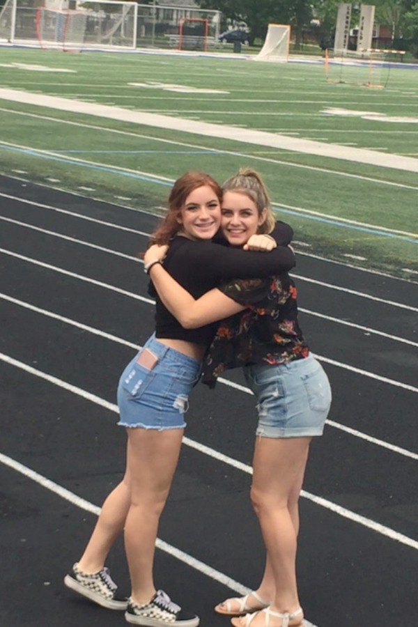Teen girls embracing on a track field. Hello Lovely Studio.