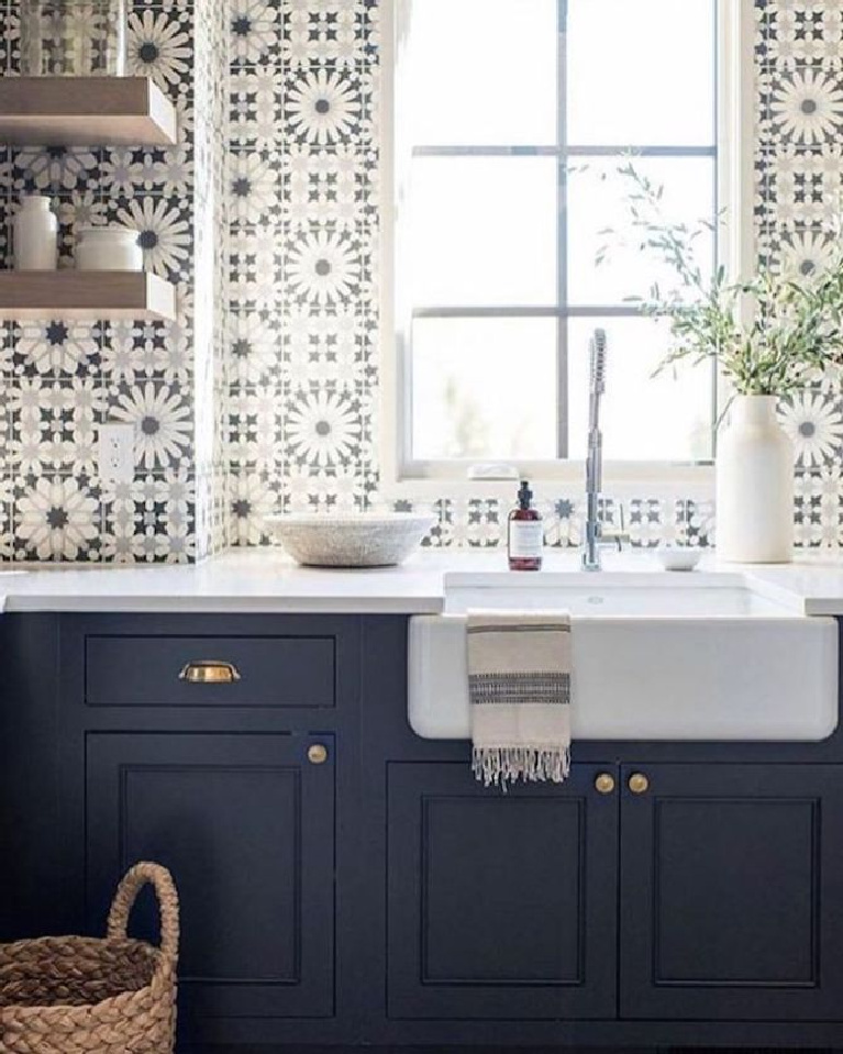 Stunning blue and white graphic tiles on sink wall of a kitchen with navy blue cabinets and farm sink. Come see 36 Best Beautiful Blue and White Kitchens to Love! #blueandwhite #bluekitchen #kitchendesign #kitchendecor #decorinspiration #beautifulkitchen