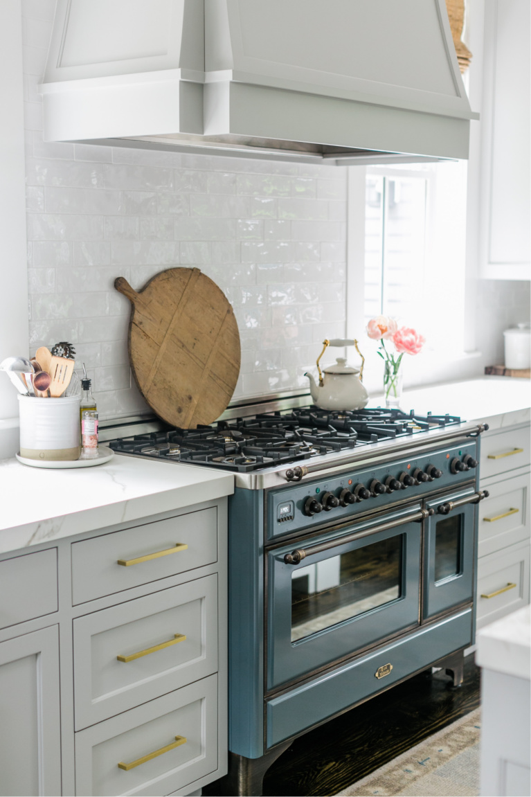 Beautiful modern farmhouse kitchen with light grey cabinets, brass hardware, and blue Ilve Majestic range - Finding Lovely. #modernfarmhouse #kitchendesigns #ilvemajestic #greykitchens